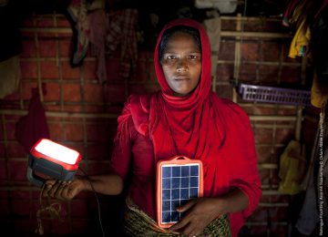 Frau die eine Solarlampe in der Hand hält, die sie durch das Projekt 394 "Eine hellere Zukunft" erhalten hat. Nun ist sie auch in der Nacht vor Kriminalität und Gewalt sicher.