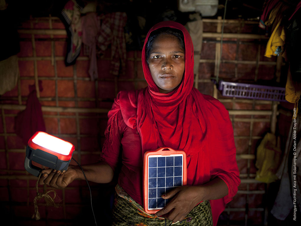 Frau die eine Solarlampe in der Hand hält, die sie durch das Projekt 394 "Eine hellere Zukunft" erhalten hat. Nun ist sie auch in der Nacht vor Kriminalität und Gewalt sicher.