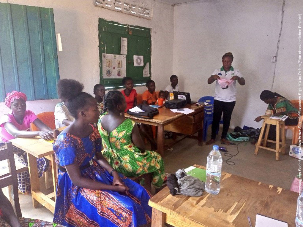 Gruppe von Frauen der Zentralafrikanischen Republik sitzen in einem Raum, wo ihnen der Umgang mit Periodenunterwäsche unseres Projektes "Tage wie diese" gezeigt wird.