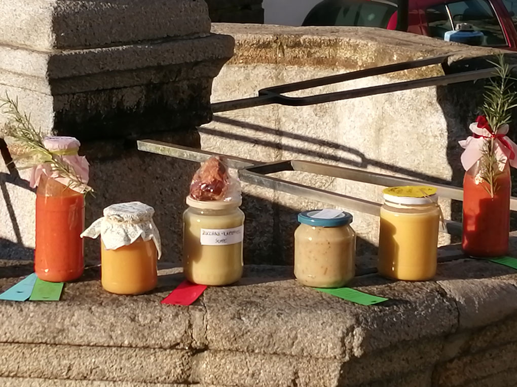 Suppen in Gläsern stehen auf einer Mauer und werden zum Verkauf angeboten.