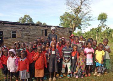 Die Kindergartenkinder von Kicuucu vor einer baufälligen Hütte, die dank ihrer Spende hoffentlich bald gegen ein wetterfestes, geräumiges, solides, gemauertes Gebäude ausgetauscht werden kann.