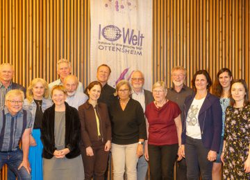 Gruppe IG Ottensheim und der Entwicklungshilfeklub stehen als Gruppe im Gemeindesaal beim 40-Jahr-Jubiläum