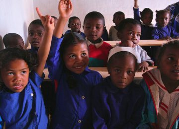 Diese Kinder können dank Vozama nun an vier Tagen pro Woche jeweils für 3 Stunden eine Volksschule besuchen. Auf dem Bild zeigen sie auf und nehmen motiviert am Unterricht teil. Viele Kinder sehen die Schule als etwas Schönes und würden gerne mehr Zeit mit Lernen verbringen.