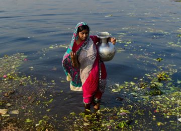 Eine Frau beim Wasserholen in Bangladesh, mit einem der traditionellen Wasserkrügen.