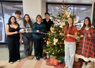 SchülerInnen des BG Schwechats stehen vor einem geschmückten Weihnachtsbaum und freuen sich über eine erfolgreiche Spendenaktion für den Entwicklungshilfeklub.