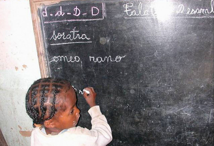 Kind schreibt mit Kreide auf die Tafel