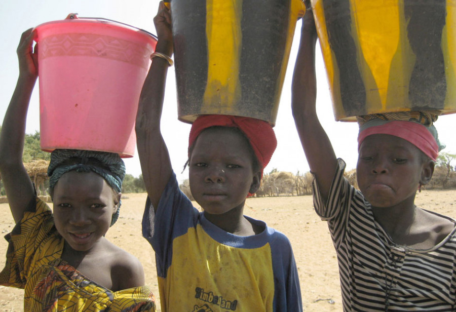 Kinder tragen auf den Köpfen Wassereimer