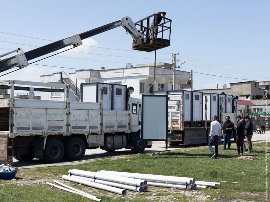 Lastwägen, Rohre und Männer zur Reparatur und dem Wiederaufbau von Sanitäranlagen im türkischen Erdbebengebiet.