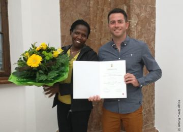Mann und Frau halten die erhaltene Urkunde und einen Blumenstrauß in der Hand
