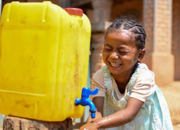Kleines Mädchen in Madagaskar wäscht sich die Hände und lacht