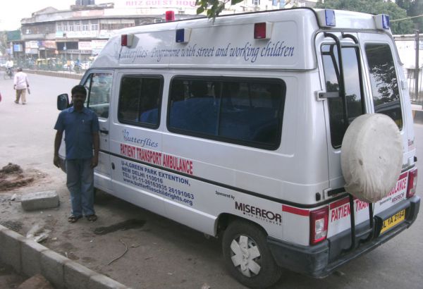 In einem Bus, der regelmäßig an bestimmten Stellen vorbeikommt, können sich die Kinder oft zum ersten Mal in ihrem Leben von einem Arzt behandeln lassen. Viele haben es dringend nötig. Mann vor Rettungsauto der Organisation Butterflies für Straßenkinder
