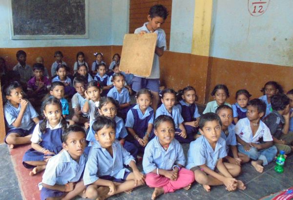 Durch das umfassende Bildungsprogramm werden die Mädchen und Buben auf ihrem Weg zu einem positiven Schulabschluss unterstützt, damit sich für sie TÜREN ÖFFNEN in eine menschenwürdige Zukunft. Indische Kinder sitzen auf dem Boden im Klassenzimmer