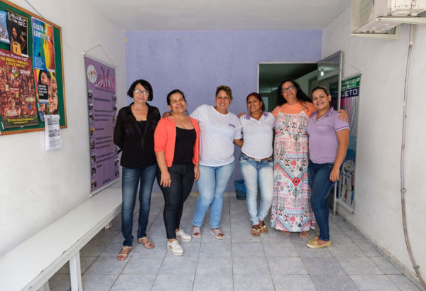 Vor diesem Hintergrund hilft das Team des Centro das Mulheres de Vitória de Santo Antão (CMV) Mädchen und jungen Frauen aus den Favelas mit psychosozialer Betreuungsarbeit, Schulunterstützung und Berufsausbildungen. Fünf Frauen stehen in einem Zimmer