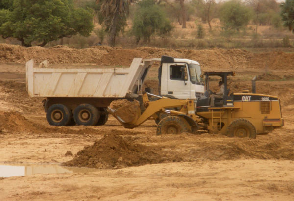 Der Bau von großen Wasserrückhaltebecken ermöglicht die Bewässerung von
Gemüsegärten für Kleinbauernfamilien der Sahelregion Burkina Fasos. Das Becken –Bouli genannt – muss mit Baggern ausgehoben werden.© Misereor/UFC Dori Wasserrückhaltebecken wird mit Bagger und Lkw gebaut