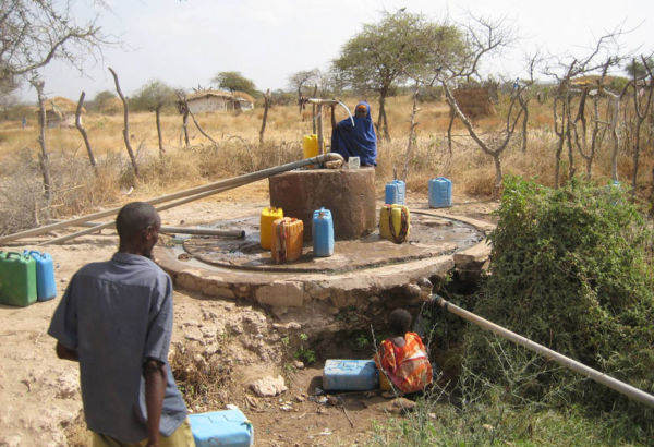 Zusätzlich wird ein 10.000-Liter-Tank errichtet, der mit einer solar- oder dieselbetriebenen Motorpumpe gefüllt wird. Das durch einen Sandfilter gesäuberte Wasser dient den Familien als Trinkwasser. Menschen am Dorfbrunnen mit Wasserkanistern